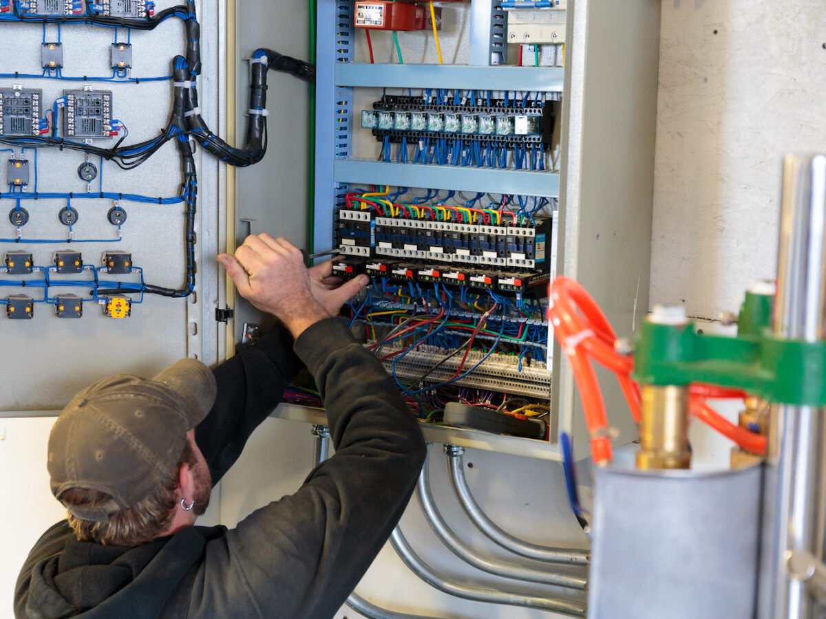 Electrician working on an electrical output control panel at a small business.